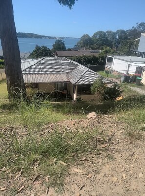 A house with a tiled roof, a visible porch, and a view of the sea. - Budget avail private Rathmines granny flat (Rathmines)