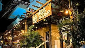 A hotel entrance with a sign reading 'Villa Jaguar,' steps leading up to the entrance, and a wooden pergola with string lights. - Villa jaguar (Fortim)