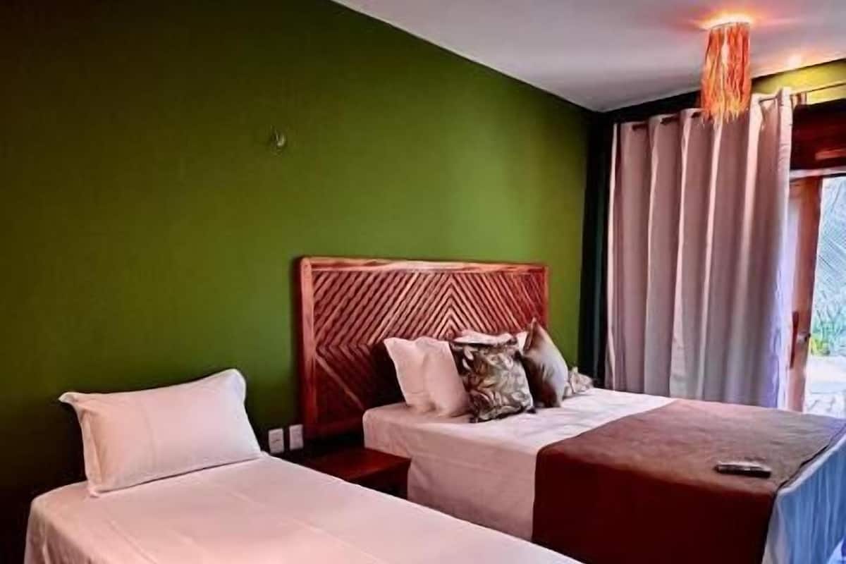 A room with two beds, a wooden headboard, and a hanging light fixture.