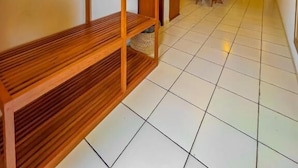 A hotel room with a wooden shelf unit, a dining table with chairs, and a tiled floor. - Villa jaguar (Fortim)