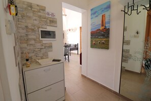 Un corridoio con parete in pietra, un dipinto raffigurante un castello, un lampadario in metallo nero e, sullo sfondo, un'area da pranzo.