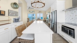 A spacious kitchen with a central island, stainless steel appliances, and a view to the outdoors. - Luxury Lagoon Front House w/ Elevator | Fire Pit | Boat Parking | Sleeps 10 (Gulf Shores)