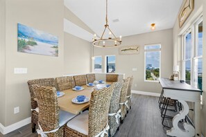 A dining area with wicker chairs, a wooden table, and a view of the outdoors. - Luxury Lagoon Front House w/ Elevator | Fire Pit | Boat Parking | Sleeps 10 (Gulf Shores)