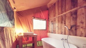 Interior de una cabaña de madera con una bañera, un lavabo y una ventana.