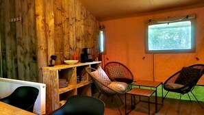 Una habitación rústica con paredes de madera, un espacio para café, dos sillas, una mesa y una ventana con vistas.
