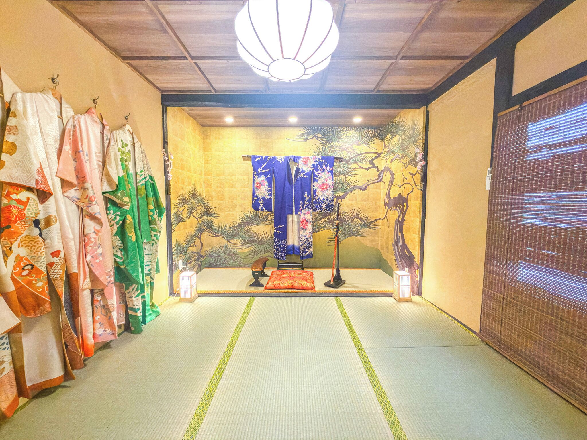 A traditional Japanese room with tatami flooring, a shoji screen, and a hanging shimenawa rope.