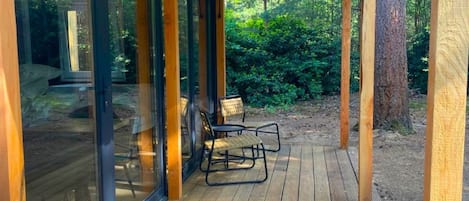 A covered wooden deck with glass doors leading to an outdoor seating area.