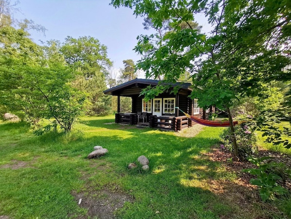 A log cabin with a porch and a hammock.
