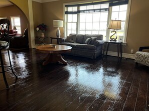 A living room with a wooden floor, a round coffee table, a sofa, and two lamps. - Valley View 4BR | Workers, Pets + Space (Valley View)