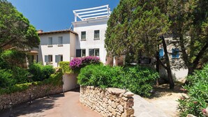 Un edificio con un muro in pietra, un balcone e un giardino con diverse piante.