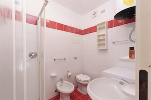 Un baño con ducha, inodoro, bidé y lavabo.
