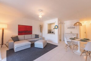 Una sala de estar moderna con sofá, reposapiés y comedor con sillas y una mesa.