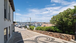 Un porto turistico con barche, un vialetto in pietra e un edificio con ampie finestre.