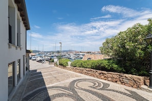 A marina with boats, a stone pathway, and a building with large windows.