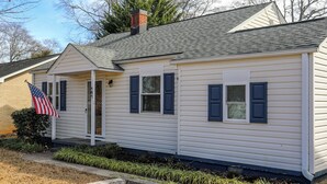 A single-story house with a front porch, a chimney, and an American flag. - Parkins Mill Bungalow (Greenville)