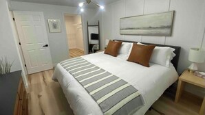 Un dormitorio con cama, mesita de noche y un cuadro en la pared.