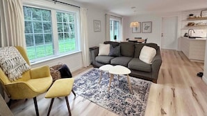 Una sala de estar con sofá, sillón, mesa de centro y alfombra.