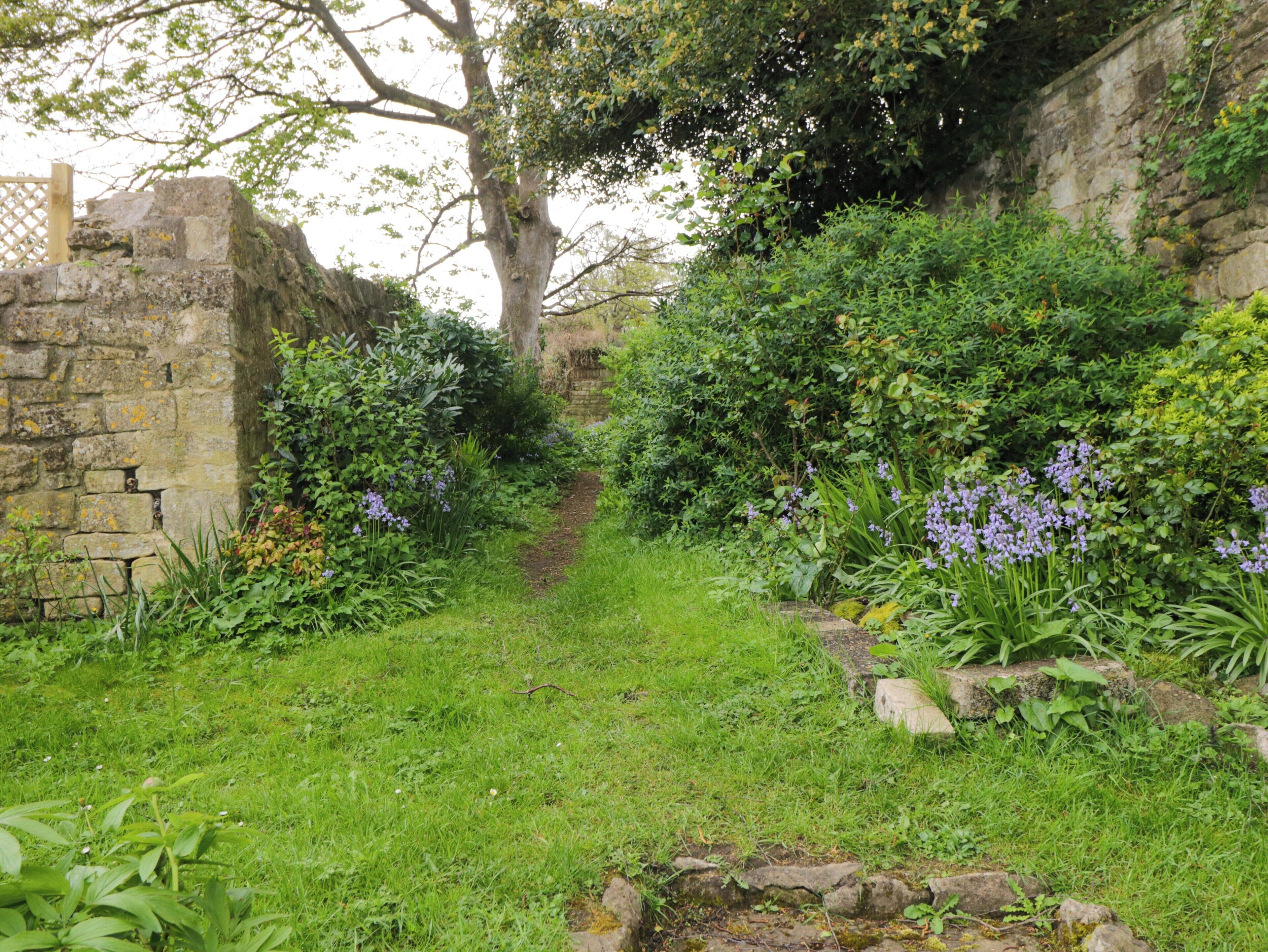 Ein Gartenpfad mit Steinmauern und üppigem Grün.