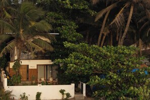 A modern house with a balcony, surrounded by lush greenery and palm trees. - Casa Melina - 1 5BR Private Beach House in Anjuna (Anjuna)