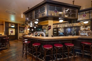 Un espace bar avec un comptoir, des tabourets et un assortiment de bouteilles et de verres.