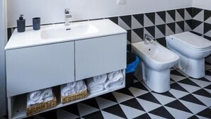 A modern bathroom with a round mirror, white sink, bidet, and tiled floor. - Nuccia Urban Loft (Naples)