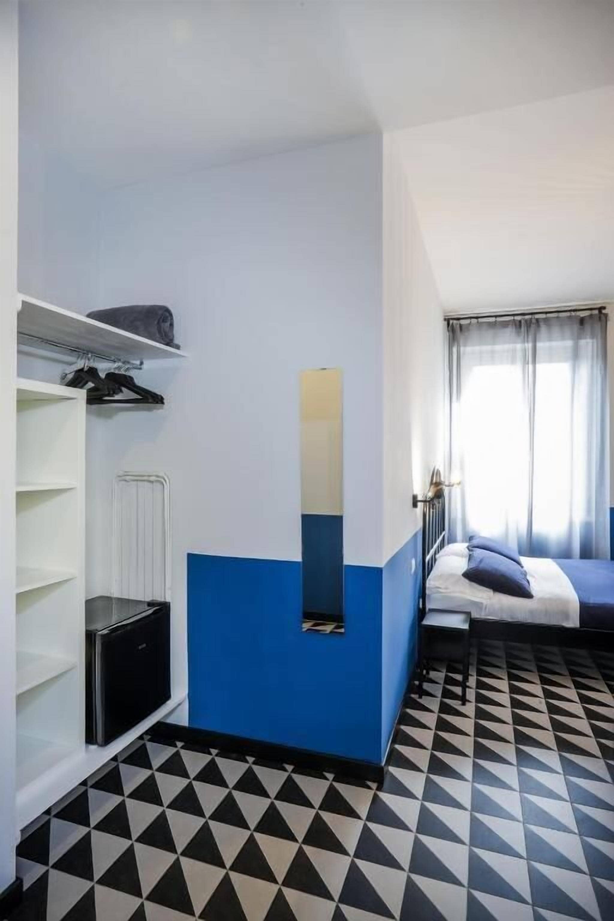 Ein Hotelzimmer mit Bett, Schrank, Heizkörper und einem Vorhangfenster.