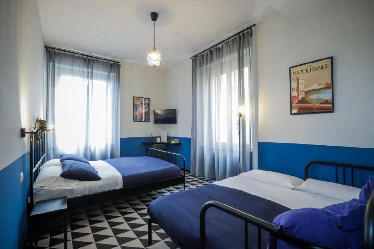 A room with two beds, a desk with a chair, a television, and a poster on the wall.