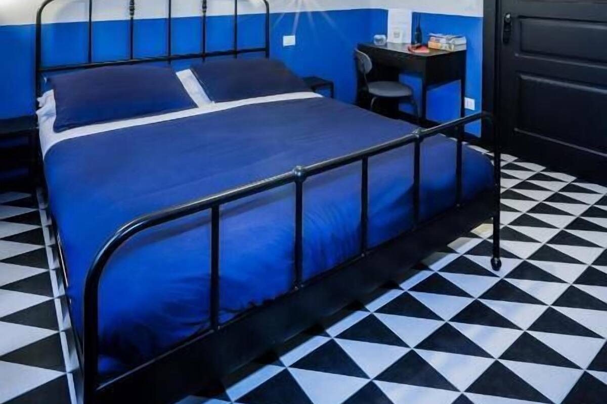 A room with a bed, a desk, a chair, a door, and a wall with a poster.