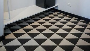 Una habitación con suelo a cuadros blancos y negros, estanterías blancas y un armario negro.