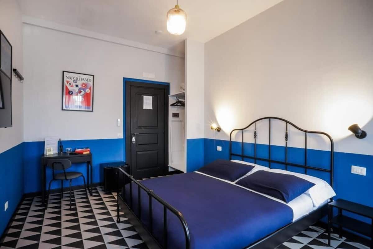 A room with a bed, a desk, a chair, a door, and a poster on the wall.