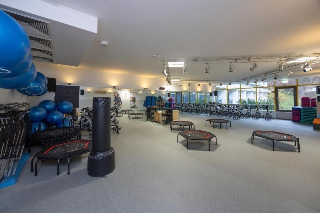 Ein Fitnessraum mit Trainingsgeräten, Matten und einem großen Fenster.
