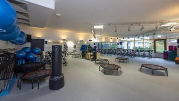 Ein Fitnessraum mit Trainingsgeräten, Matten und einem großen Fenster.