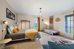 Una habitación con una cama, una cama individual, un escritorio, una silla, una lámpara, una ventana y una pared con un cartel de ciudad.