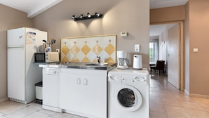 A compact kitchen with a refrigerator, microwave, sink, and washing machine. - Gîte La Rémondière – 20 min from Puy du Fou (Pouzauges)