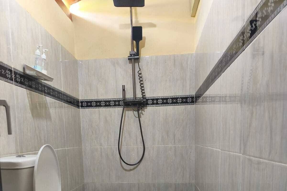 Un baño con inodoro, ducha y paredes de cerámica.