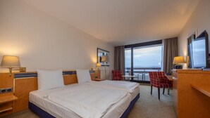 A hotel room with a large bed, a desk, a chair, and a view of the sky. - Modern Room With Pool And Pets Near Neheim Boutiques (Arnsberg)