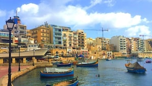 Un muelle con barcos amarrados, edificios al fondo y un cielo despejado.