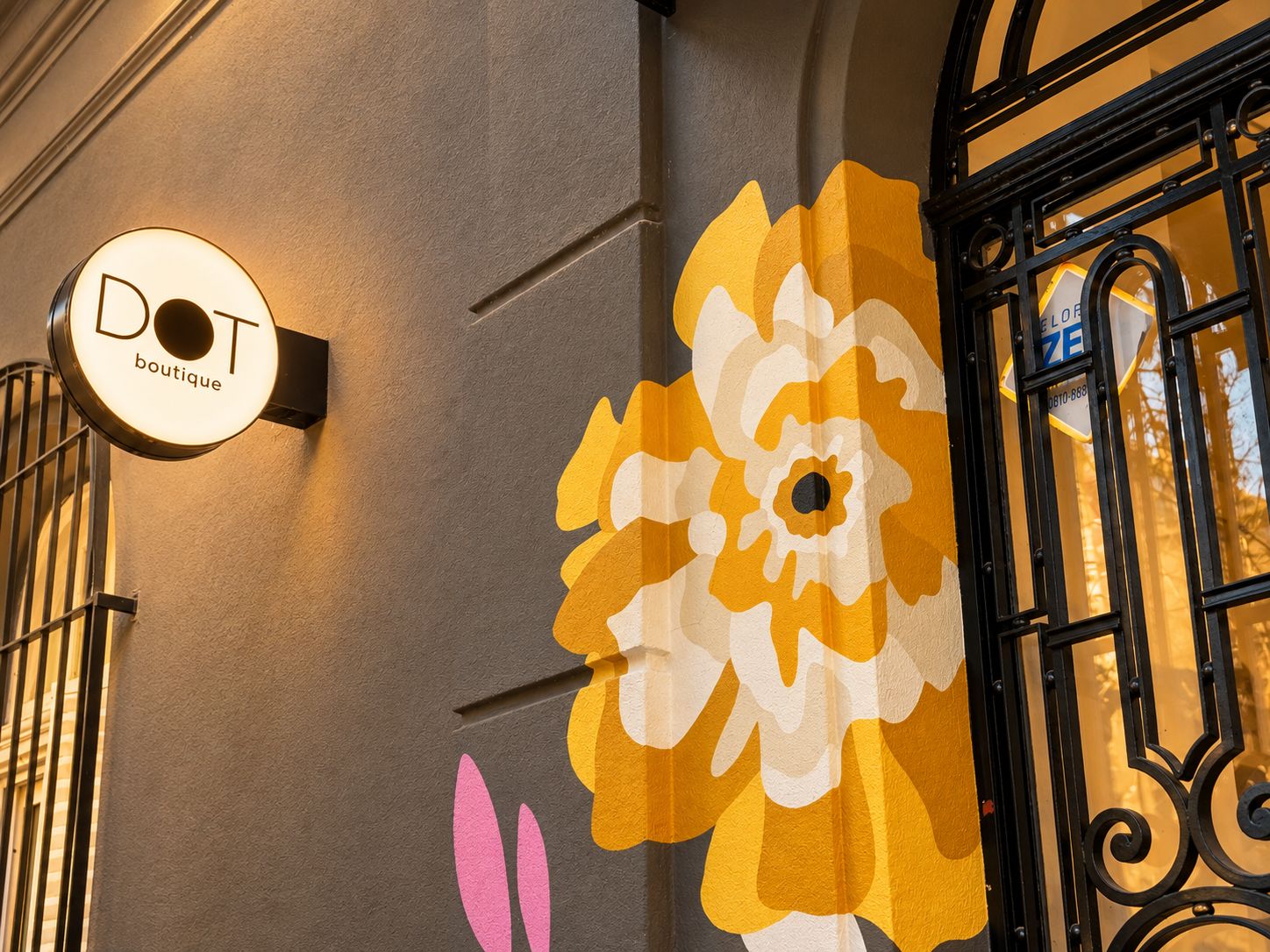 Eine Gebäudefassade mit einem großen floralen Wandgemälde und einem Schild mit der Aufschrift 'DOT boutique'.