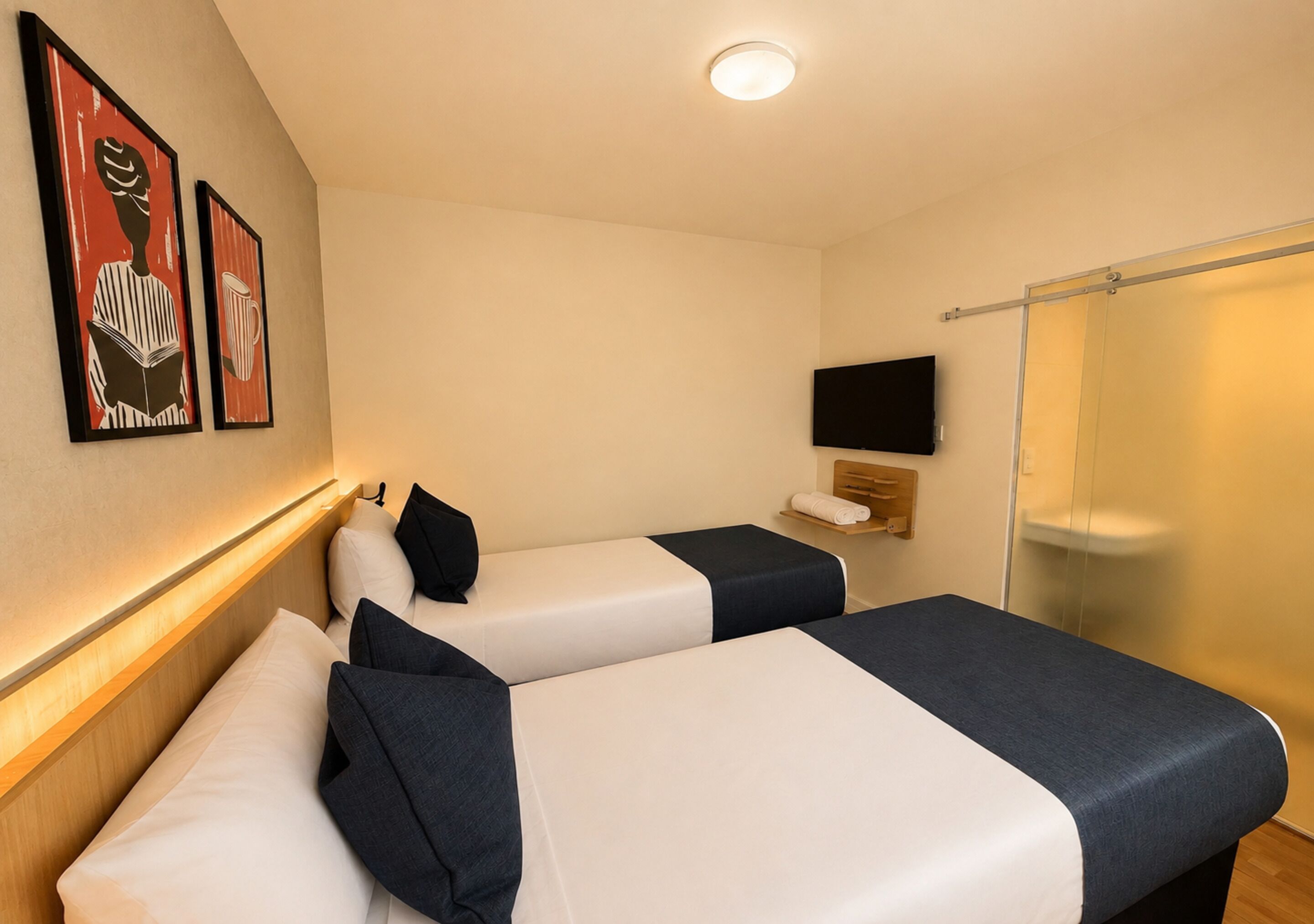 Ein Hotelzimmer mit zwei Betten, einem Fernseher und einer Dusche.