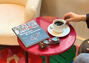 Un libro titulado 'Bicicletas de Carrera' sobre una mesa roja, junto a una taza de café y unas gafas de sol.