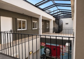 Un edificio residencial de varios niveles con techo de vidrio, escalera en espiral y un mural en la planta baja.