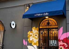 A building facade with a blue awning, a door with ornate metalwork, and a large floral mural. - Los Patios de Julia by DOT Boutique (Buenos Aires)
