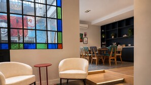 A room with two white armchairs, a small red table, a colorful rug, and a stained glass window. - Los Patios de Julia by DOT Boutique (Buenos Aires)