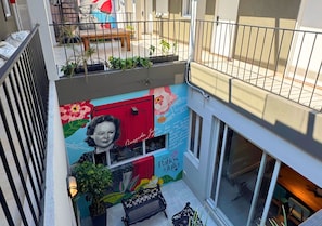 A multi-level building with a balcony, outdoor seating, and a mural with floral and text elements. - Los Patios de Julia by DOT Boutique (Buenos Aires)