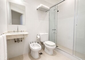 Un baño moderno con lavamanos, bidé, inodoro y cabina de ducha de vidrio.