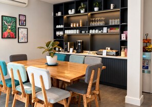 A modern cafe with a wooden table, chairs, and a counter with various items. - Los Patios de Julia by DOT Boutique (Buenos Aires)