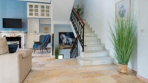 Ein Wohnzimmer mit Sofa, Fernseher, Treppe und einem Gemälde.