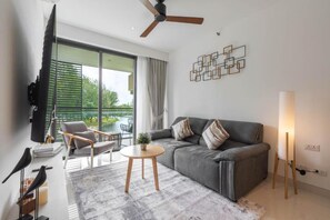 Ein modernes Wohnzimmer mit einer Couch, Sesseln, einem Fernseher und einem großen Fenster.