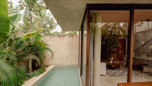 A modern outdoor area with a pool, stone wall, and tropical plants. - Modern 3BR Villa with 2 Pools & Rooftop Lounge (Tulum)