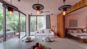 A modern room with a dining table, two sofas, a ceiling fan, and large windows. - Modern 3BR Villa with 2 Pools & Rooftop Lounge (Tulum)